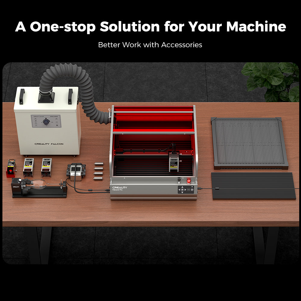 A workspace setup featuring versatile accessories for a machine. From left to right: a mounted motor, a control box with ventilation hose, an FDA Class 1 certified CrealityFalcon Falcon2 Pro 40W Enclosed Laser Engraver and Cutter Master Engraving Bundle, several small brackets, a metallic frame, and a black grid mat. Text reads "A One-stop Solution for Your Machine" and "Better Work with Accessories.